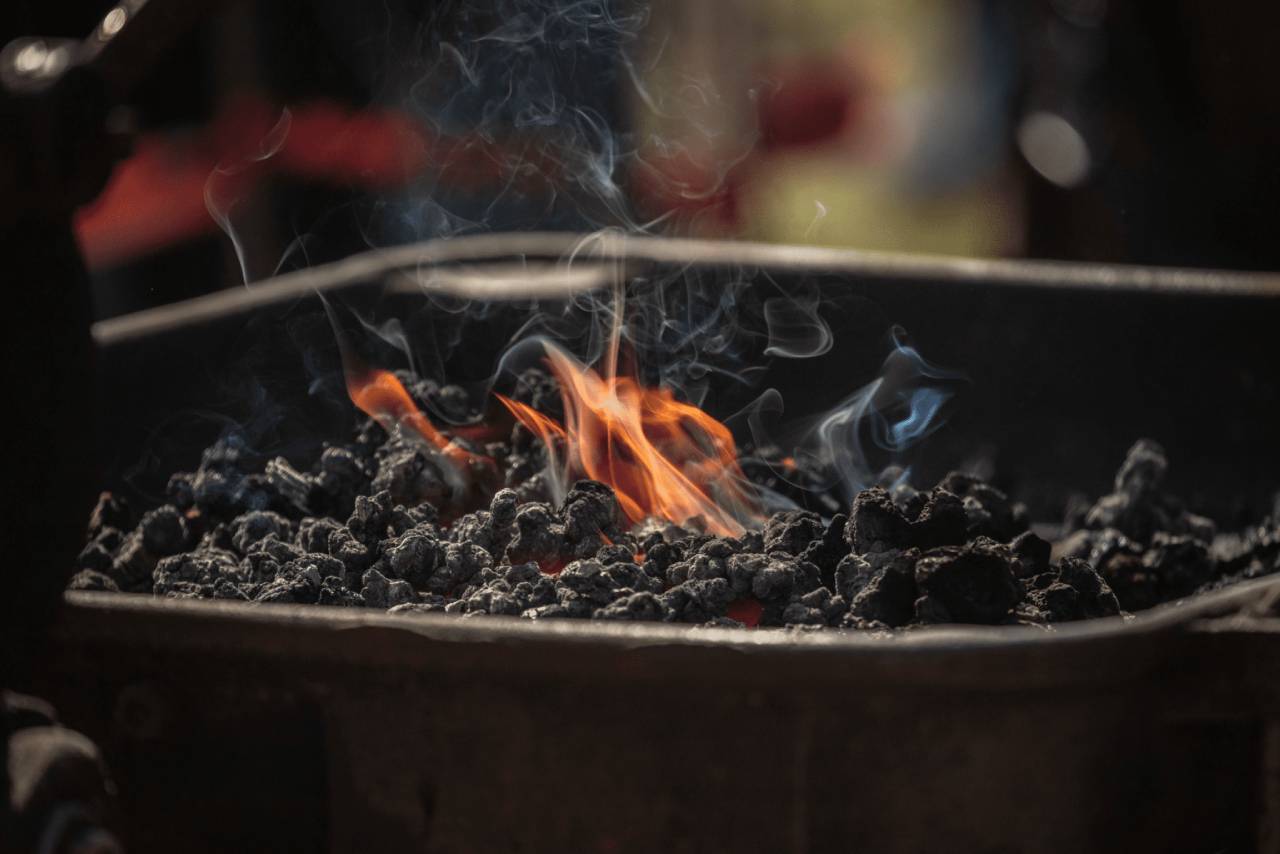 Coal filled fire pit with smoke, flames and blurred background